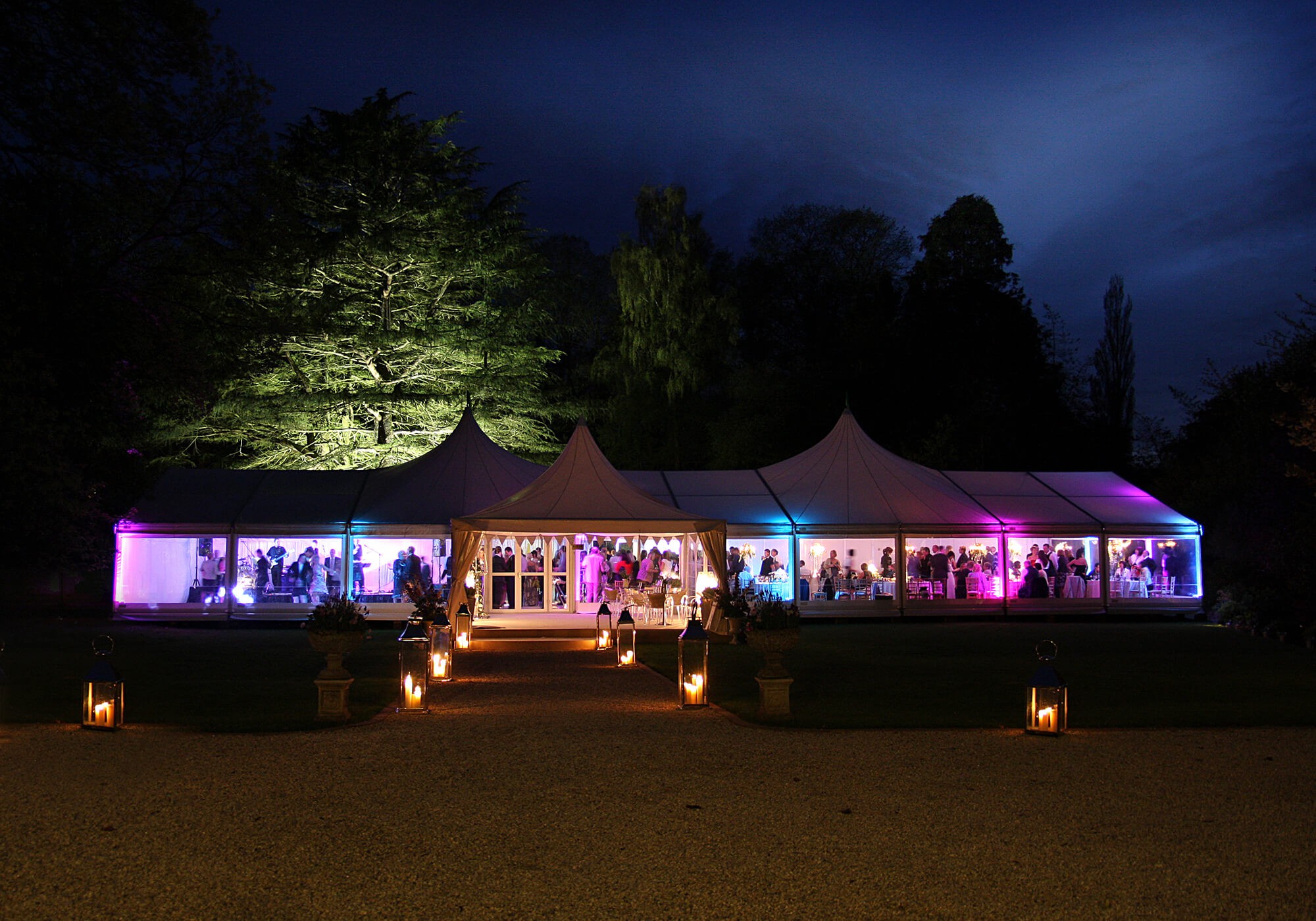Party marquee lit up at night with peaked roofs